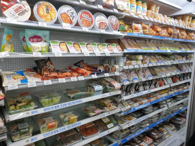 An aisle inside a Korean convenience store showing shelves stocked with various instant ramen and unique Korean snacks.
